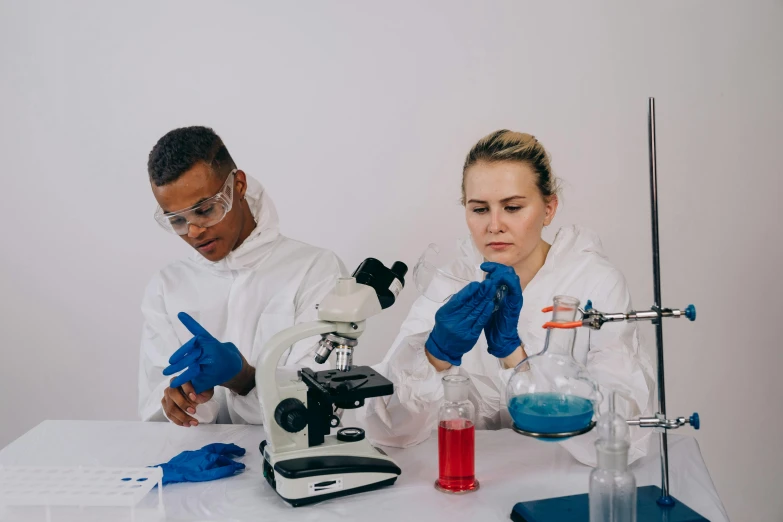 a man and woman dressed in white standing behind a microscope