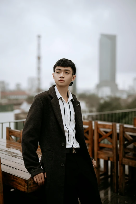 a boy in a black suit stands on a bench