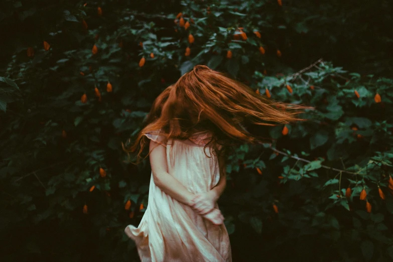 an orange haired woman wearing a white dress with her hair blowing in the wind