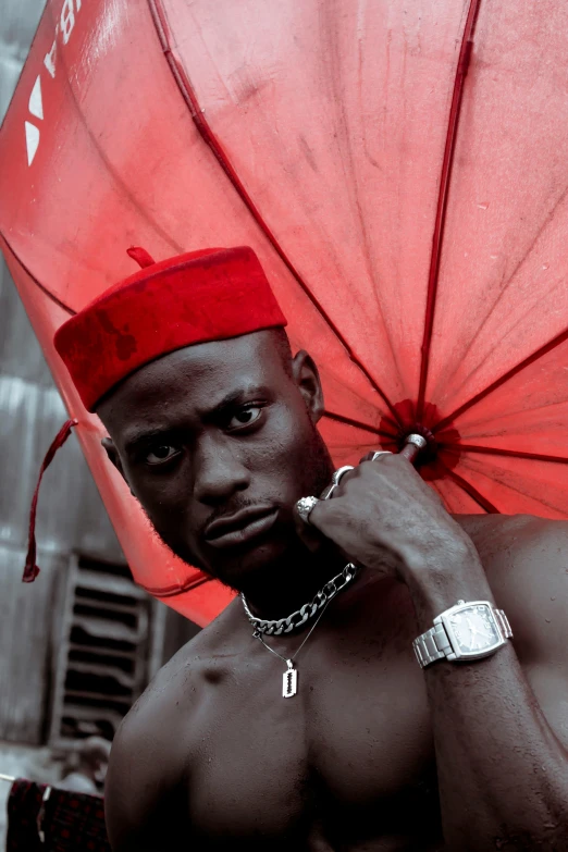 black man wearing a red hat holding a red umbrella