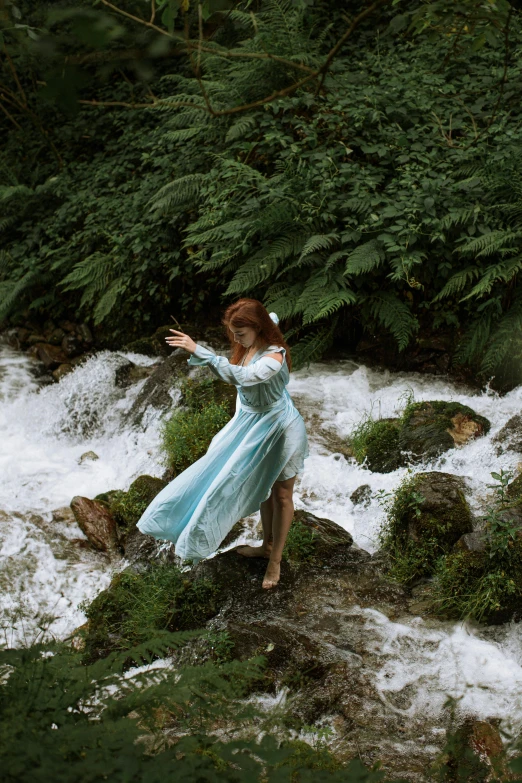 a woman is wearing a blue dress by some water