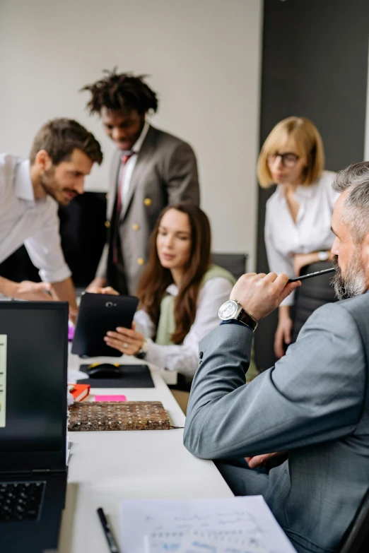 business people looking at a laptop screen while others watch