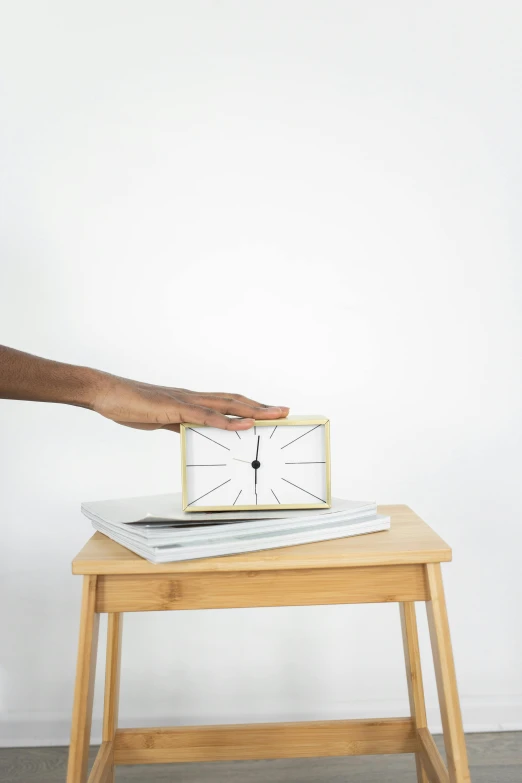 an alarm clock on a wooden stool in front of a wall