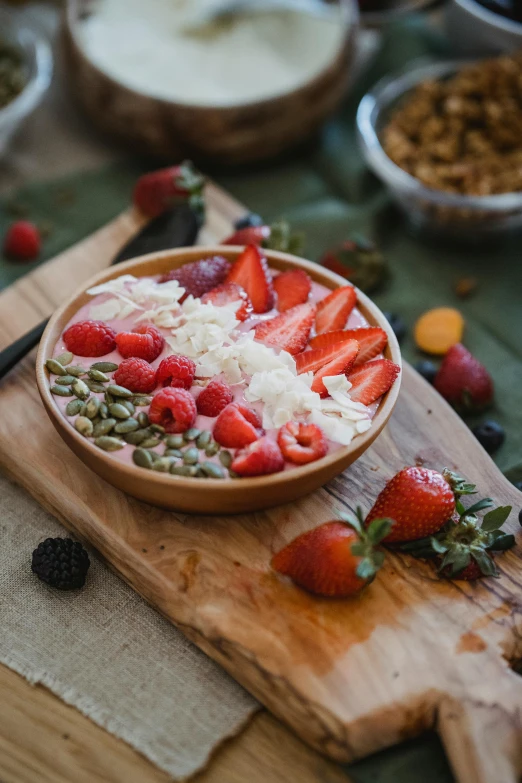 sliced strawberries in a wooden bowl atop a  board