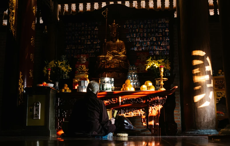 the man in a black coat sits at the alter