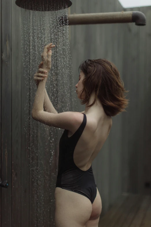 a  woman wearing black panties and standing under a shower