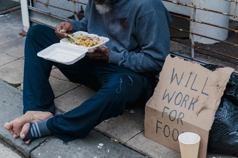 man sitting down while holding a bowl with food