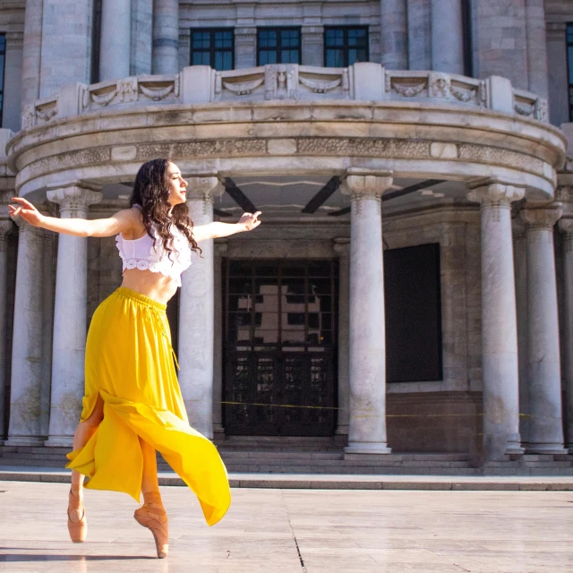 a woman in a long yellow skirt dancing outside