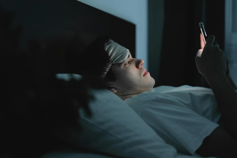 man in a blindfold with cell phone in dark room