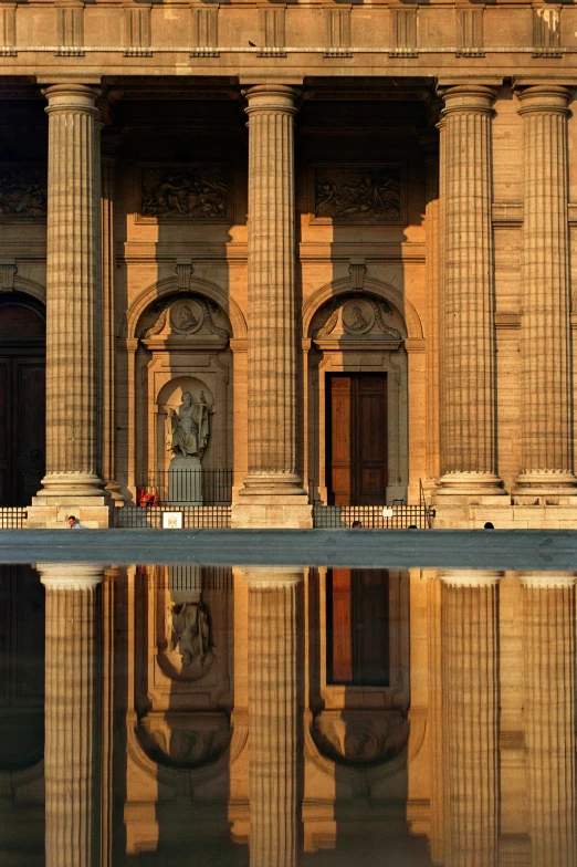 a large building with stone columns next to a body of water