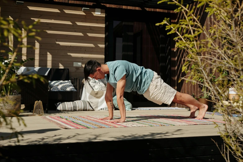 an older man is doing yoga on a deck