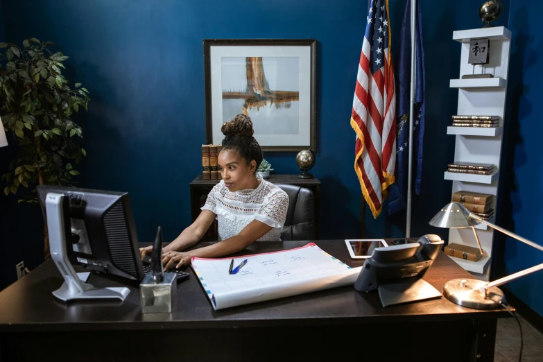 a woman sitting at her desk in front of a monitor