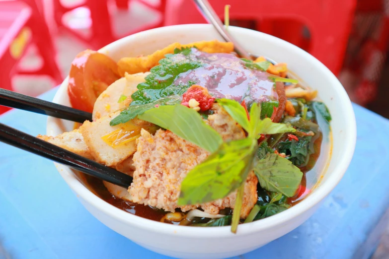 a bowl of vegetable soup with chopsticks and vegetables