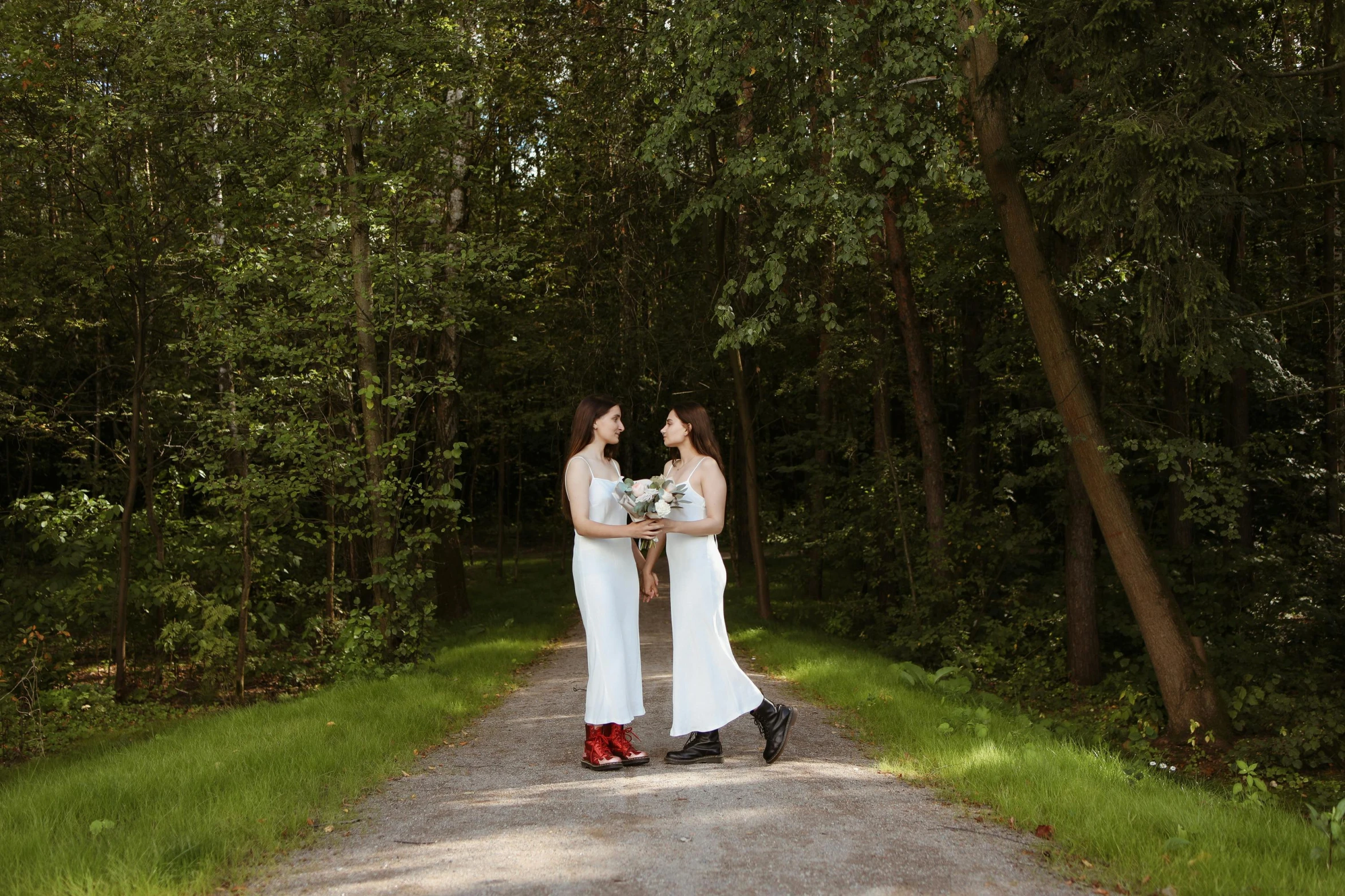 two women in white dresses posing on a dirt path