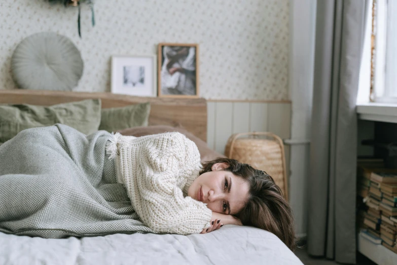 a girl lays in her bed as she covers herself