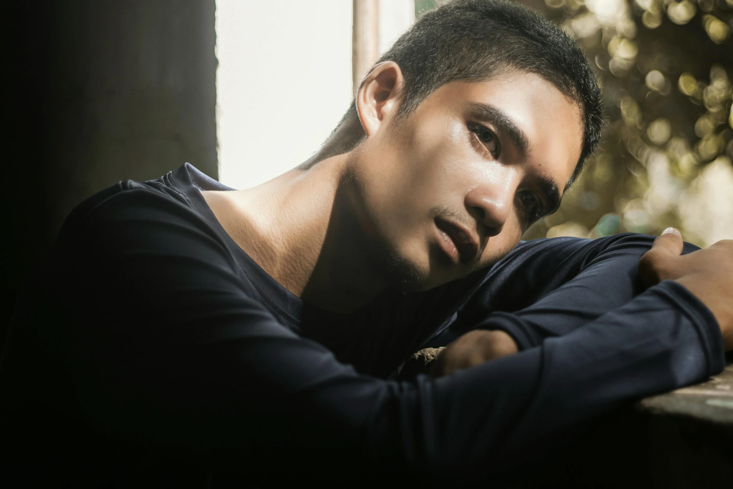 a man leans on a window ledge next to a tree