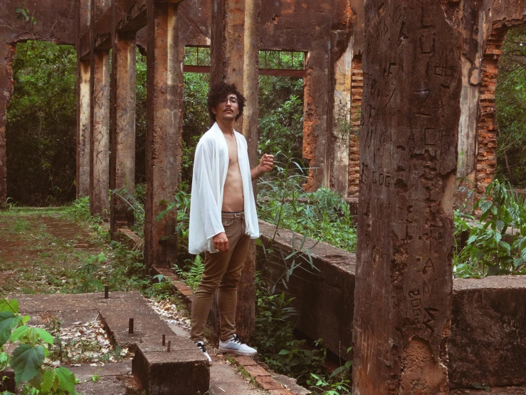 man with  and tan pants in ruins surrounded by trees