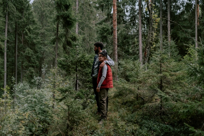 the man and woman are walking through the woods