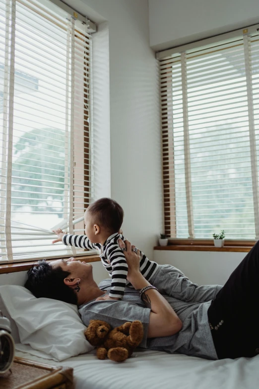 a man with a child laying on top of a bed