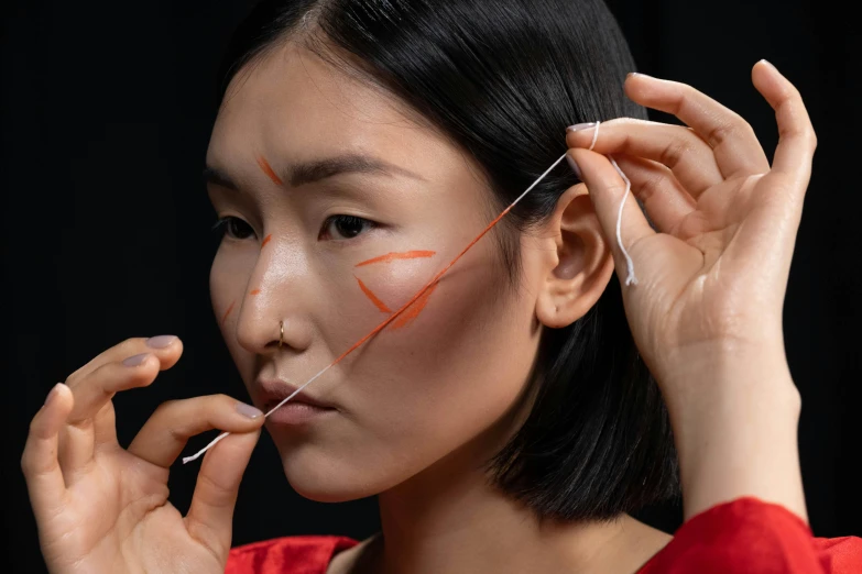 an asian woman holding scissors to her ears