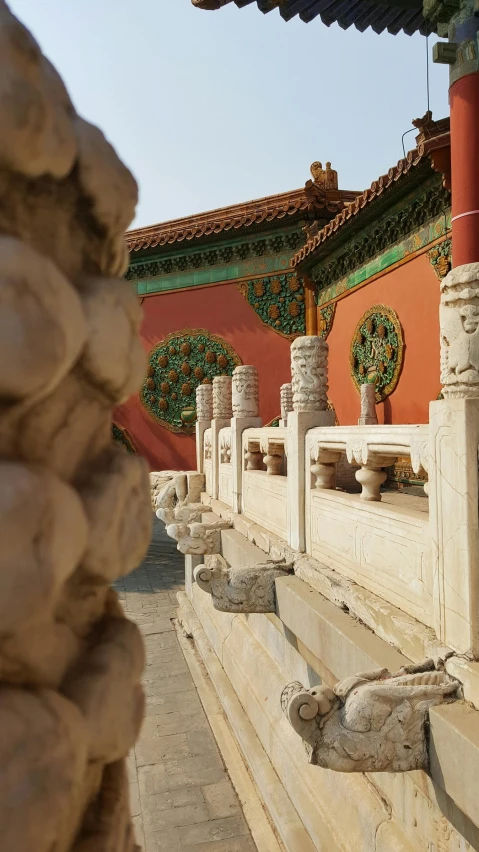 a row of stone pillars next to a building with colorful decorations on top