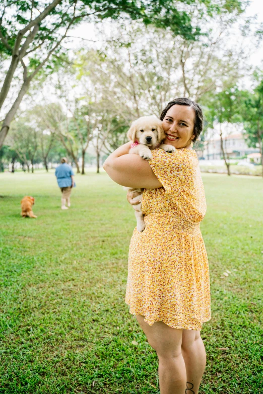 a woman holds her dog outside in a park