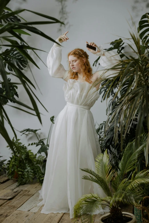 a woman is posing in a white dress and is holding up soing