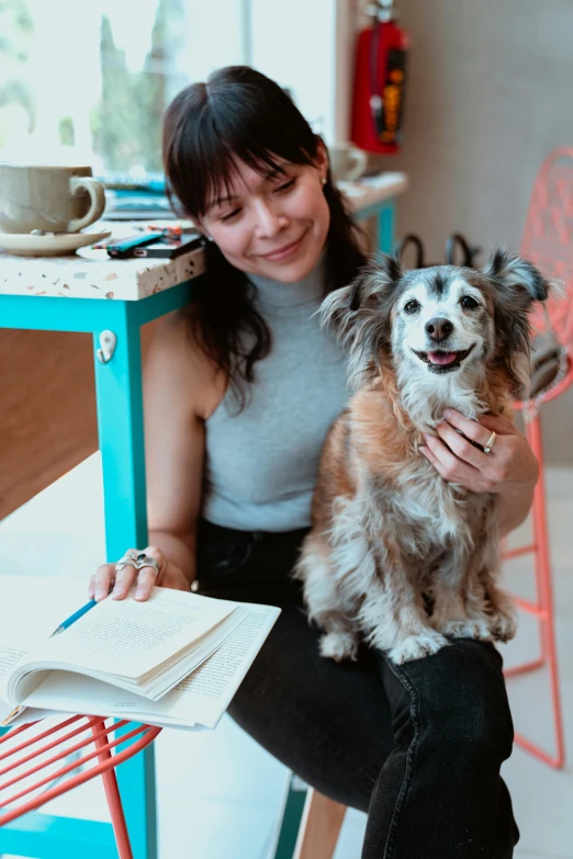 a woman sitting in a chair holding her dog