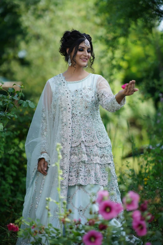 a lady is walking through the flower garden wearing a white dress