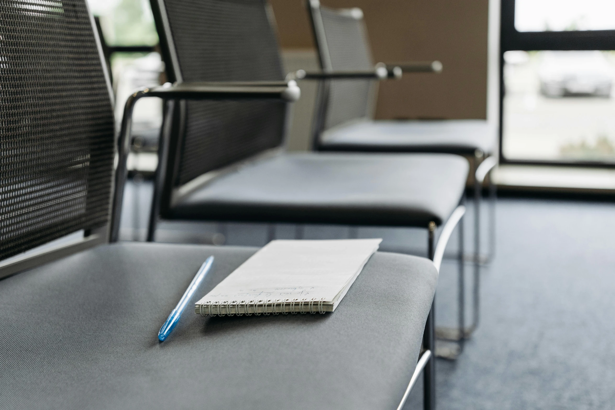 an empty book with pen and pad on a conference chair