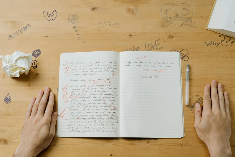 the person holds their hand near an open notebook with writing on it