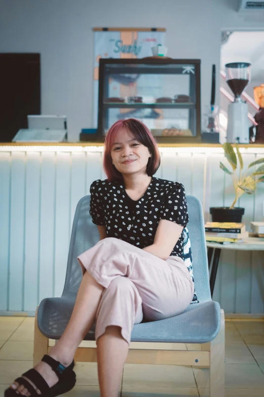 a woman sitting in a blue chair with pink hair