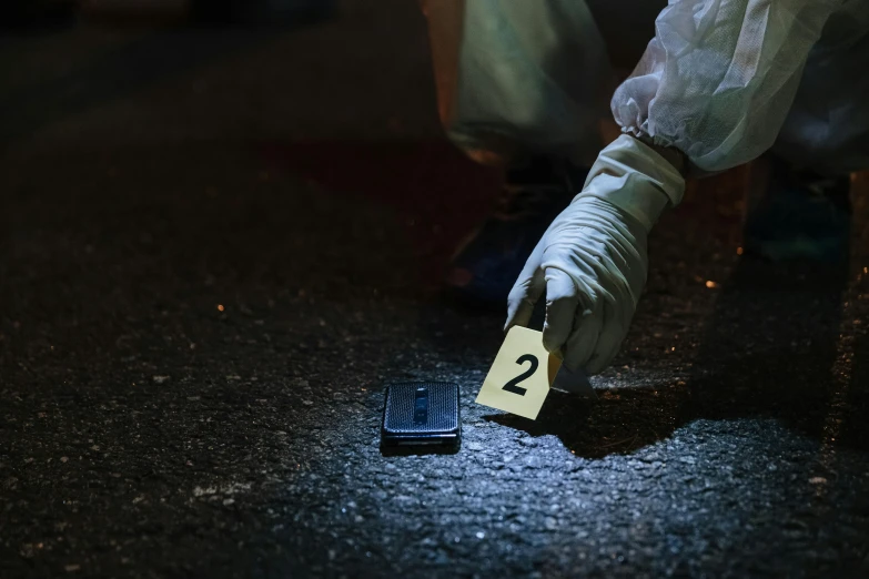 a person in white gloves holds onto a yellow paper with two numbers