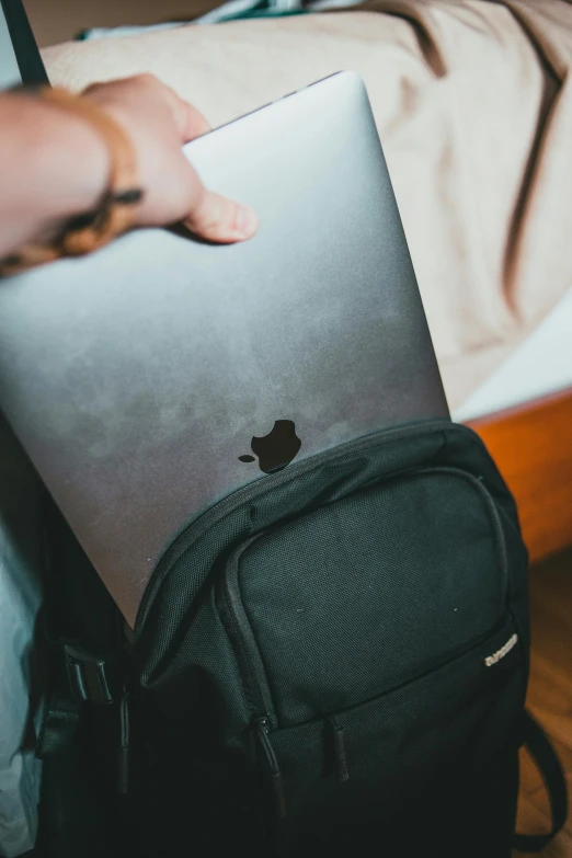 a backpack on the floor with an apple laptop in the lap