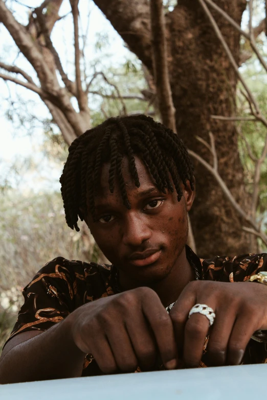 a person standing in front of a tree and wearing rings