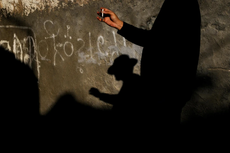 two shadows cast by a person holding up a cigarette