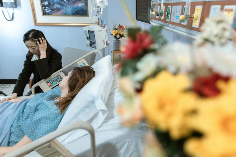 two women in hospital room with a patient looking at a newspaper