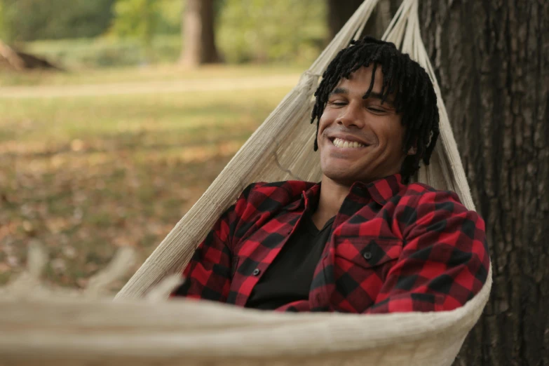 a man resting in a hammock near a tree