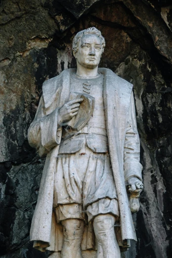 a statue of a man standing next to a rock