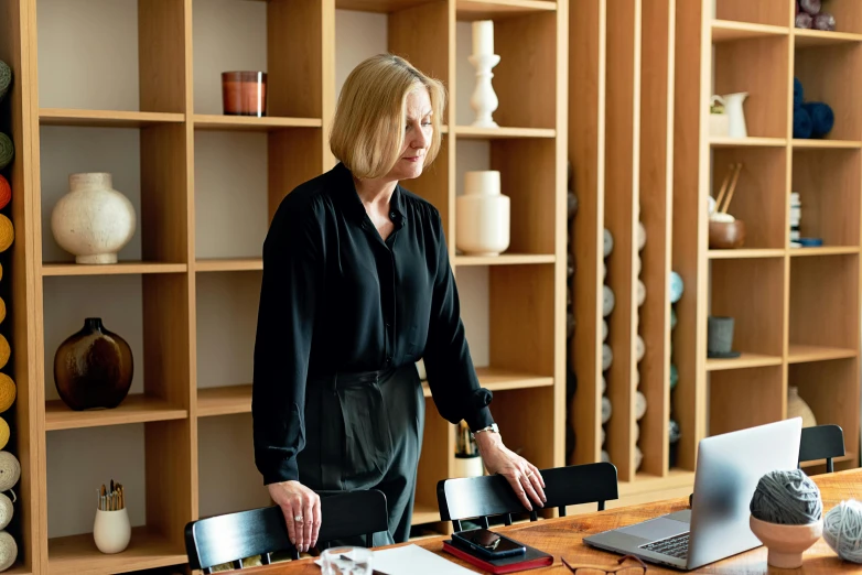 a woman standing in a home office with a desktop and laptop computer on the counter