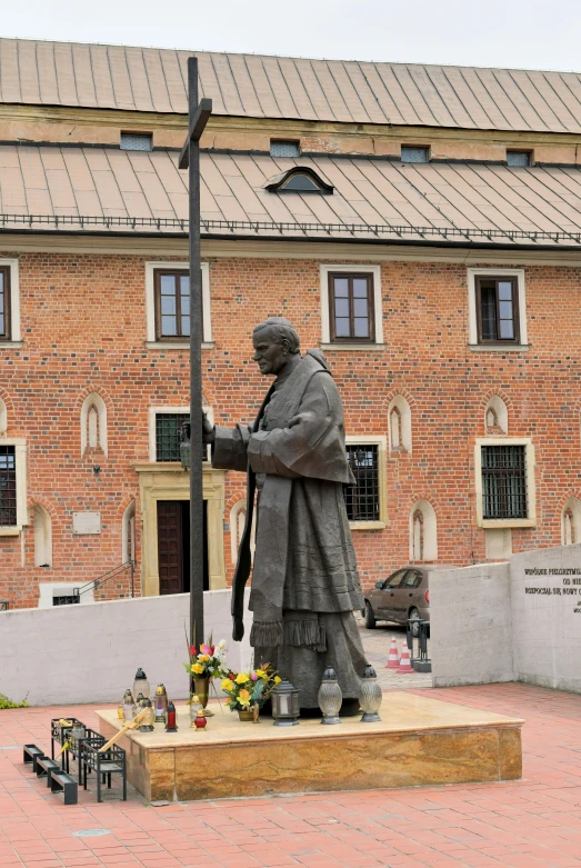 a statue of a man holding a cross next to flowers