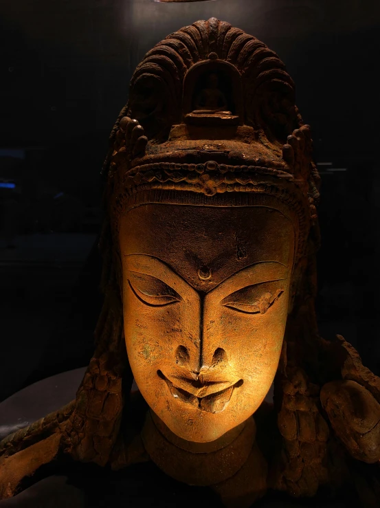an oriental buddha head lit up by a lamp