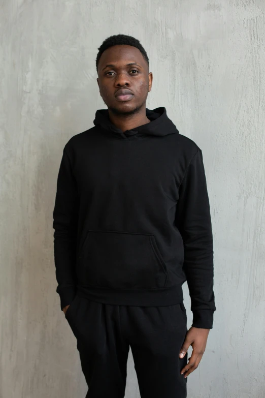 a young black man standing against a wall