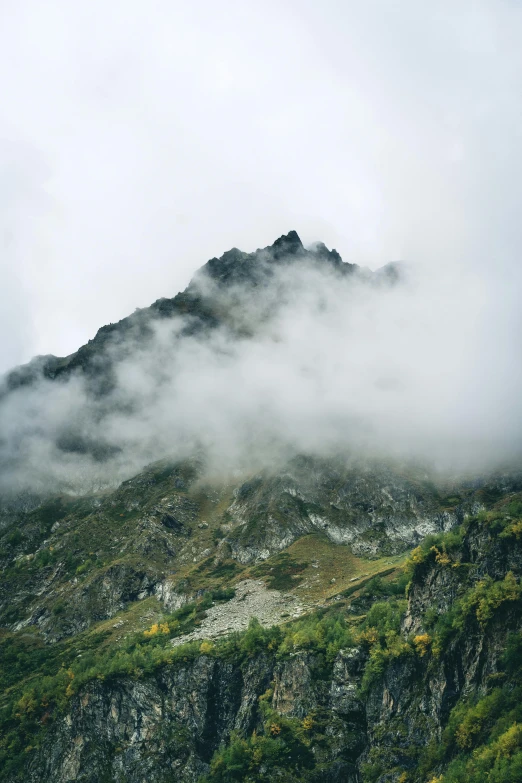 a rocky mountain with low clouds covering it