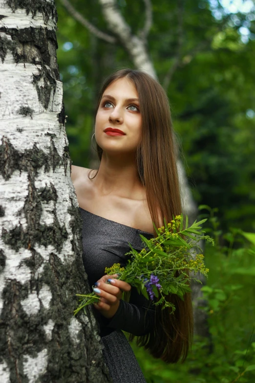 a young lady standing up against a tree