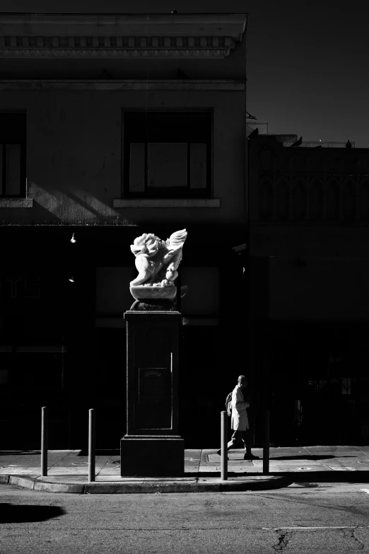 black and white pograph of statues next to buildings