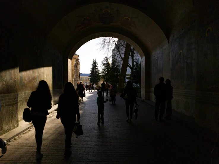 the people are walking under the tunnel in the dark