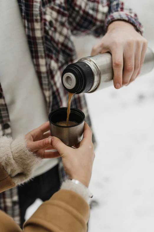 a couple pouring coffee into the same cup