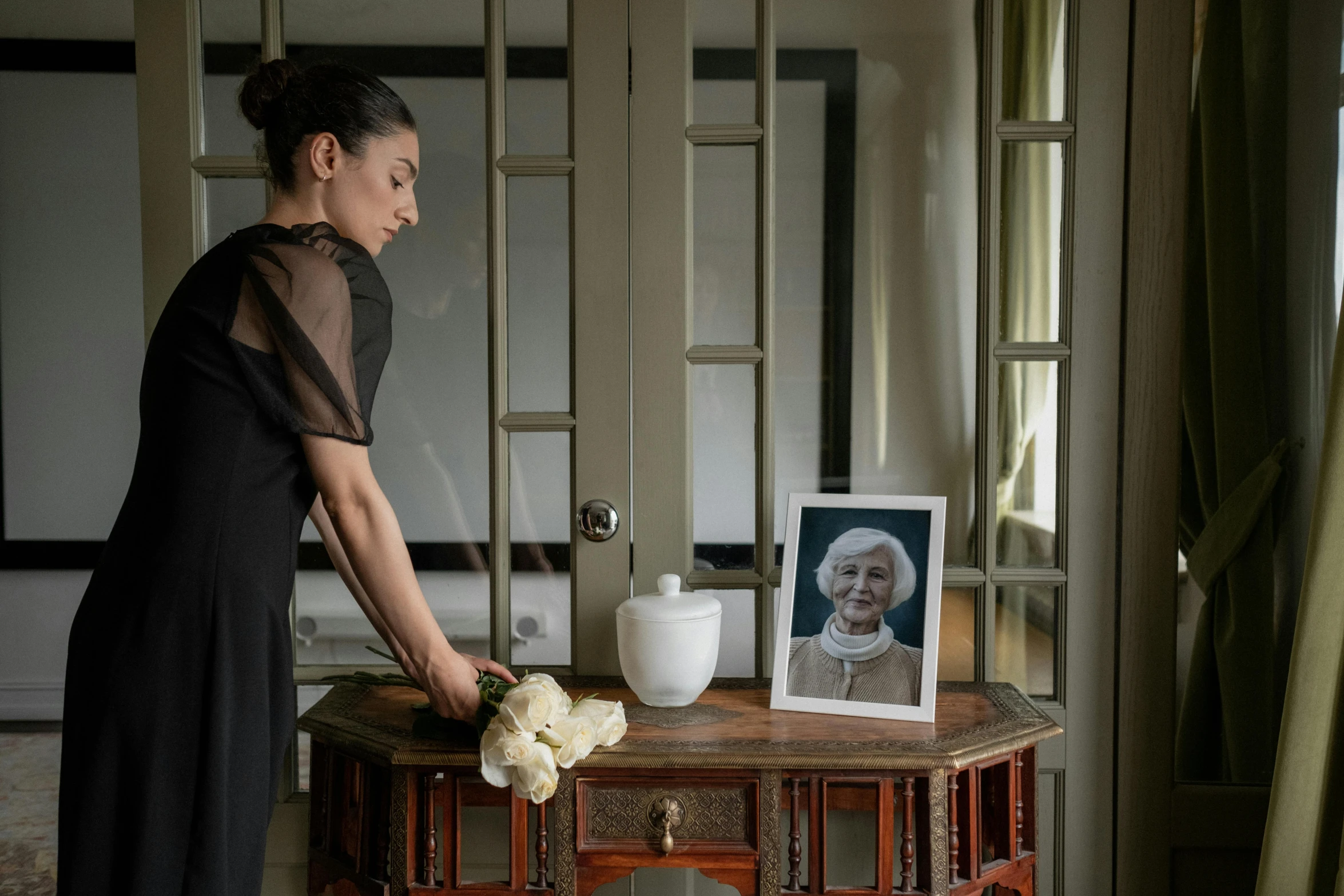 a woman is holding a doll near a painting and a desk