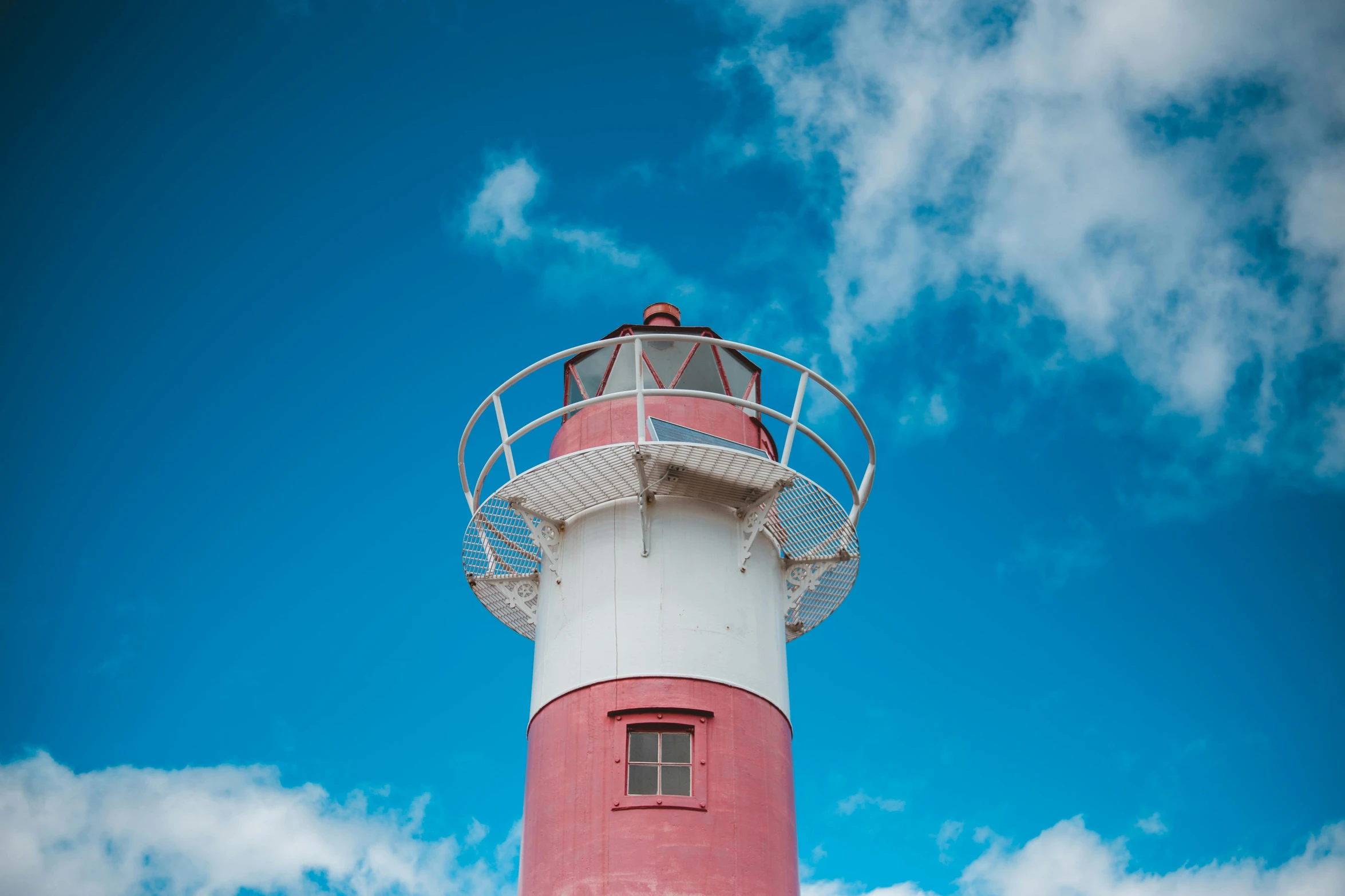 a pink and white light house with a clock at the top